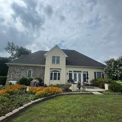 Exterior view of a modern home with a stone facade, patio, and landscaped garden.