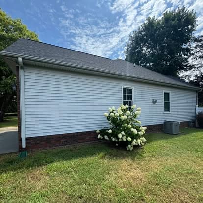 Side view of a white house with a landscaped yard and blue sky.