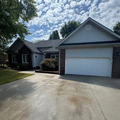 Single-story house with a two-car garage and landscaped front yard under a cloudy sky.